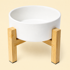 White elevated ceramic pet bowl with reversible bamboo stand on a warm cream background
